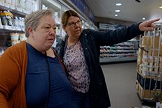 EEn dame wijst een oudere vrouw de weg in een supermarkt