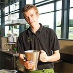jongemanin een keuken met een kan in handen